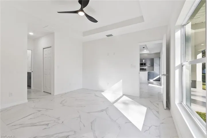 Empty room featuring ceiling fan and a raised ceiling