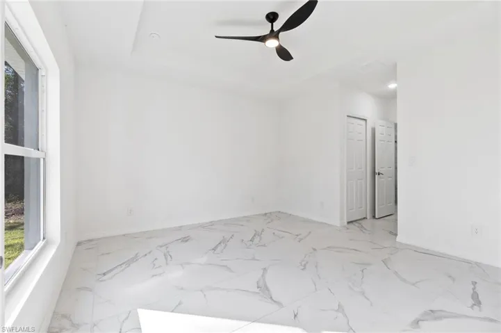 Empty room with ceiling fan and a raised ceiling