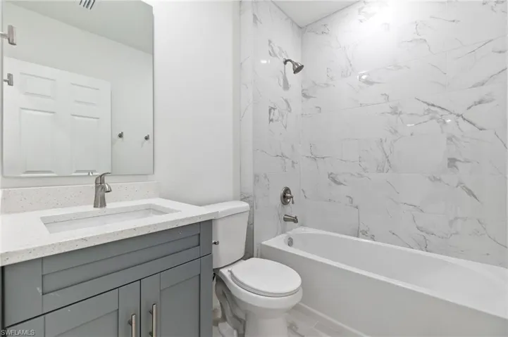 Full bathroom featuring toilet, tiled shower / bath, and vanity