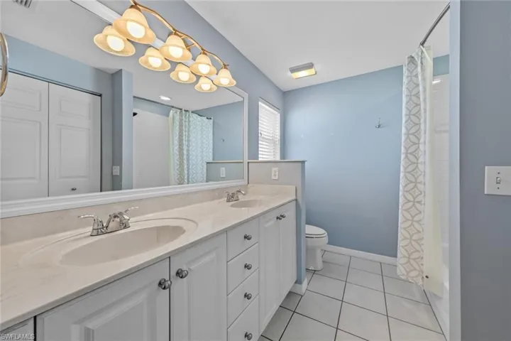 Full bathroom featuring vanity, shower / bath combo with shower curtain, tile patterned floors, and toilet