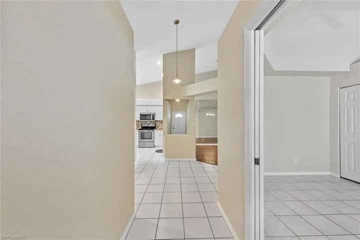 Hall with vaulted ceiling and light tile patterned flooring