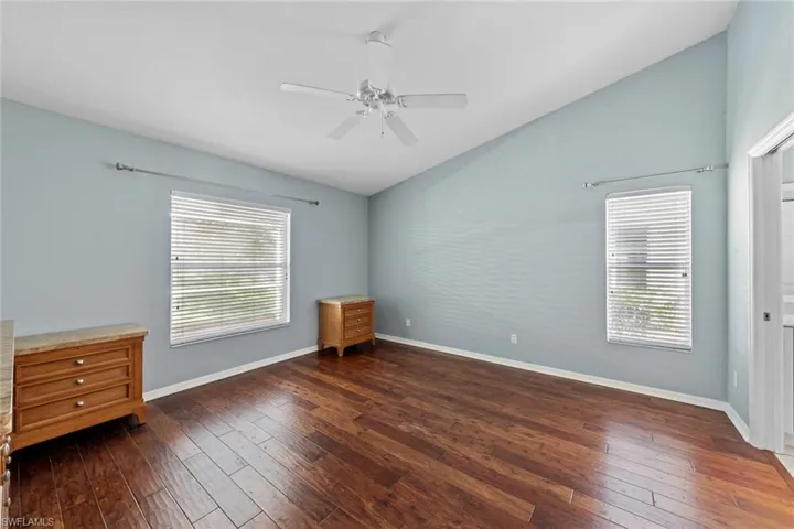 Unfurnished room with dark wood-type flooring, ceiling fan, and vaulted ceiling