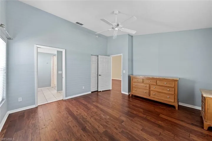 Unfurnished bedroom with dark wood-type flooring, ceiling fan, and connected bathroom