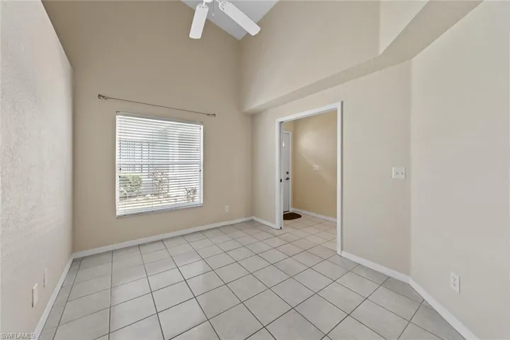 Empty room featuring a towering ceiling, ceiling fan, and light tile patterned floors