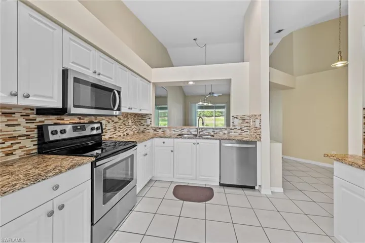 Kitchen featuring stainless steel appliances, white cabinets, sink, tasteful backsplash, and light tile patterned flooring