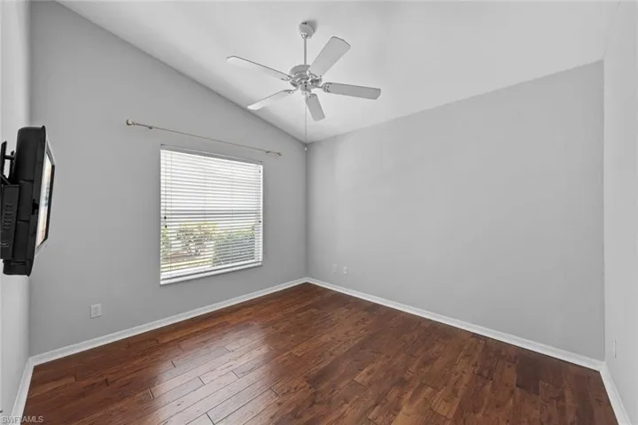 Spare room with hardwood / wood-style flooring, ceiling fan, and vaulted ceiling