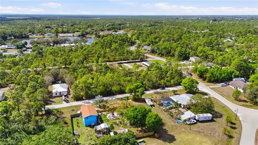 Aerial perspective of suburban area with a heavily wooded area and a large body of water