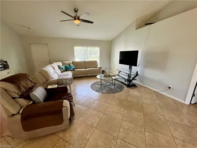 Living room featuring ceiling fan, light tile patterned floors, and cathedral ceiling