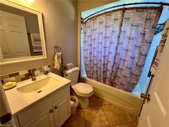Full bathroom with shower / tub combo, tasteful backsplash, vanity, tile flooring, and toilet