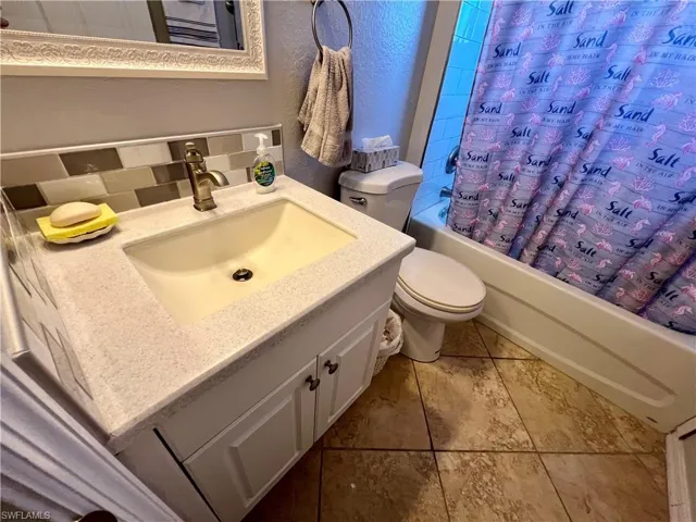Full bathroom with tile flooring, vanity, shower / tub combo, and toilet