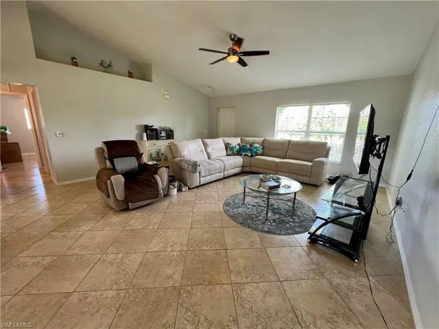 Tiled living room with ceiling fan and cathedral ceiling
