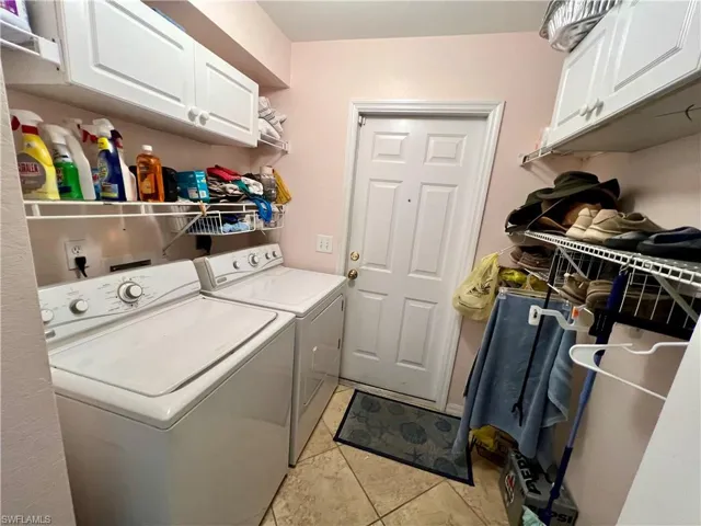 Laundry room featuring washer and dryer, light tile  floors, and cabinets
