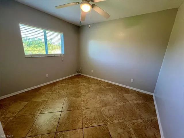 Guest bedroom featuring ceiling fan and tile floors.