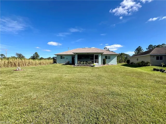 Back of house featuring a yard and screened lanai