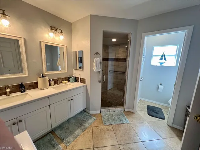 Bathroom featuring tile floors, vanity, an enclosed shower, and toilet