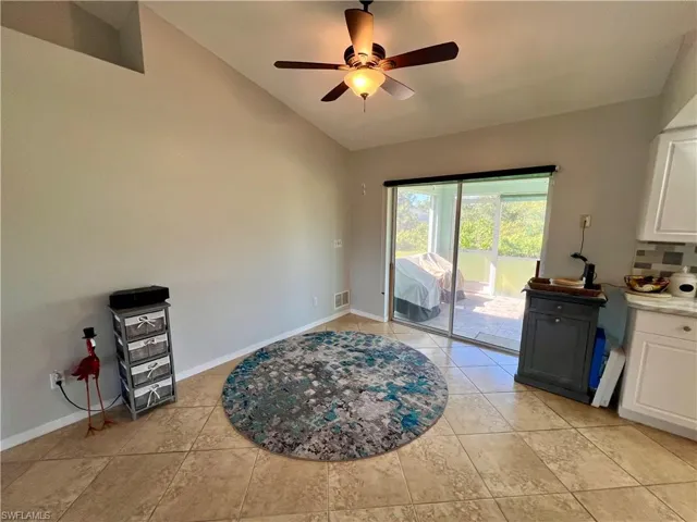 Dining space with vaulted ceiling, ceiling fan, and light tile patterned flooring