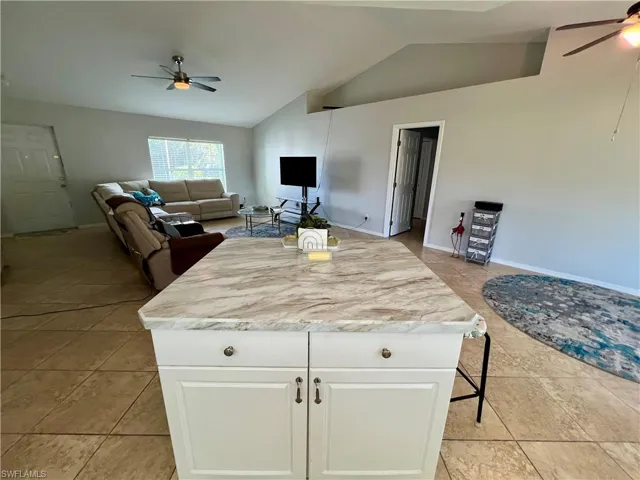 Kitchen with white cabinetry, light tile patterned flooring, and cathedral ceiling