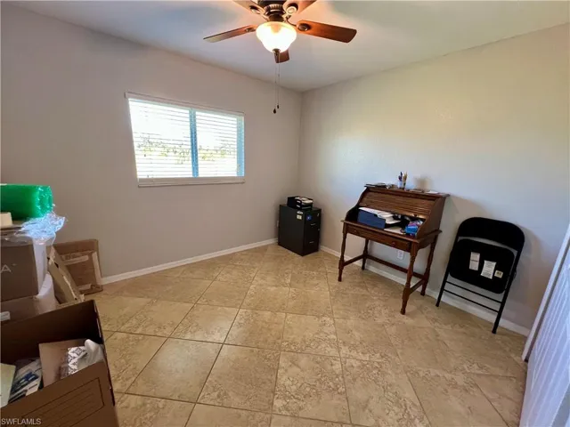 Guest bedroom with ceiling fan and tile floors.