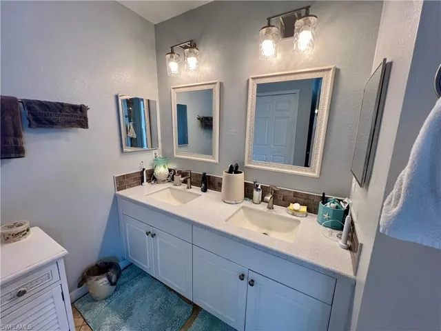 Primary Bathroom featuring tile floors and dual sinks with tiled backsplash.