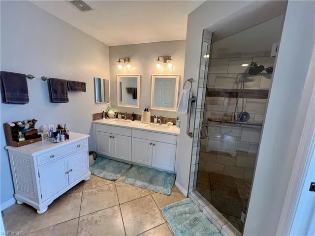 Primary Bathroom featuring tile flooring, vanity, and a large walk in shower with door