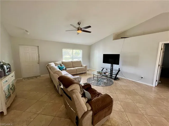 Tiled living room featuring cathedral ceiling and ceiling fan