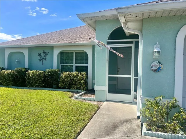 Doorway to property featuring a lawn