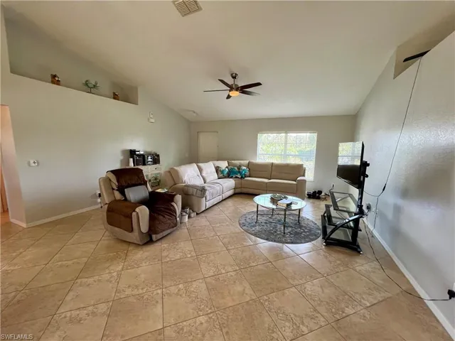 Living room with ceiling fan, cathedral ceiling, and light tile patterned floors