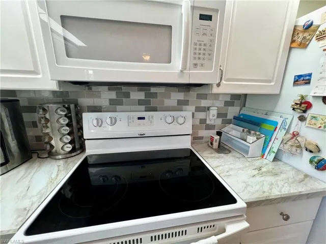 Kitchen with white cabinets, white appliances, and tiled backsplash