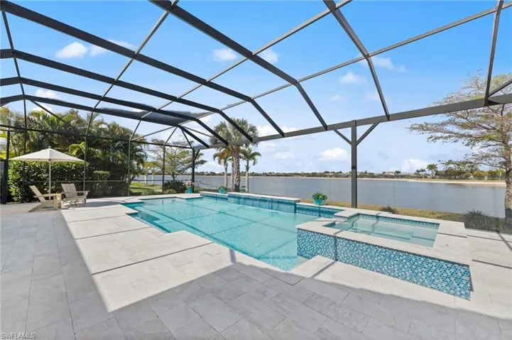 Integrated pool / spa with a lanai, a sunroom, a water view, and a patio area
