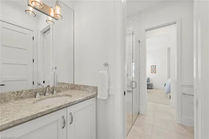 Ensuite bathroom featuring vanity, a shower stall, and light tile patterned floors