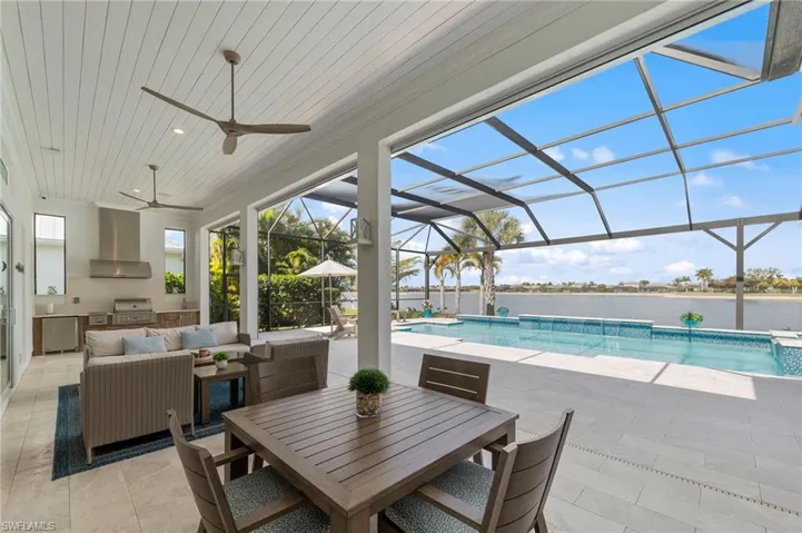Swimming pool featuring area for grilling, a patio area, a sunroom, a lanai, and an outdoor living / dining area New OUTDOOR KITCHEN (December 2018), New electric Storm Smart HURRICANE SHUTTERS (March 2019), New SHIPLAP CEILING & CROWN MOLDING (May 2020), New CEILING FAN (October 2024)