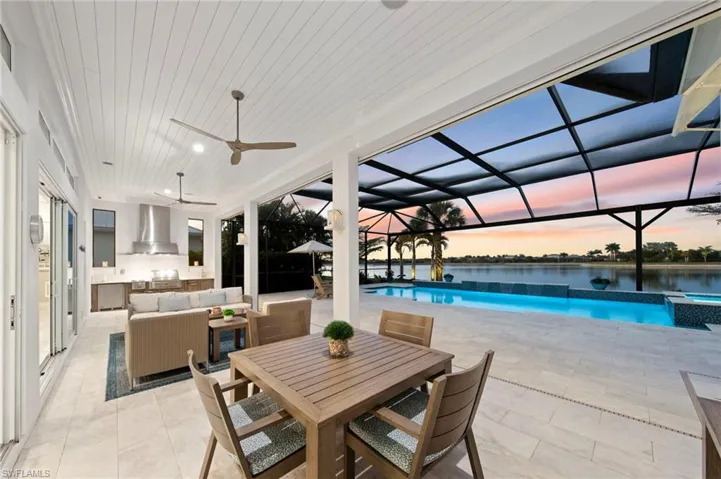 Patio terrace at dusk with a lanai, a patio, ceiling fan, outdoor lounge area, and a pool with connected hot tub New OUTDOOR KITCHEN (December 2018), New LANDSCAPE LIGHTING (February 2019) New electric Storm Smart HURRICANE SHUTTERS (March 2019), New SHIPLAP CEILING & CROWN MOLDING (May 2020), New CEILING FAN (October 2024)
