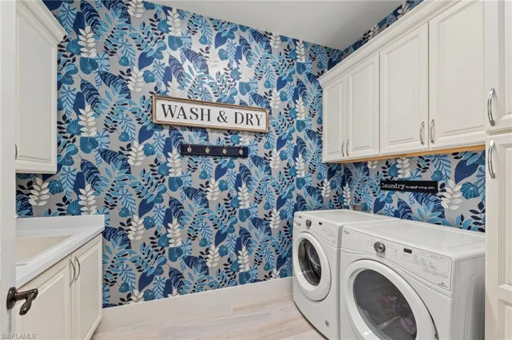 Laundry room featuring wallpapered walls, cabinet space, washer and clothes dryer, and light wood-style floors New LIGHT FIXTURE (November 2018), New ECOBEE THERMOSTAT (December 2019), New OCCUPANCY SENSOR (December 2019), New WALLPAPER (June 2020)