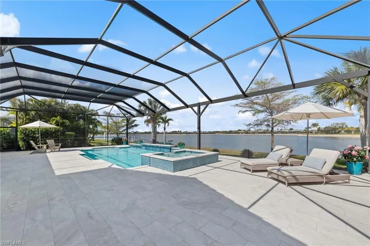 Combined pool / hot tub featuring a sunroom, a lanai, a water view, and a patio area