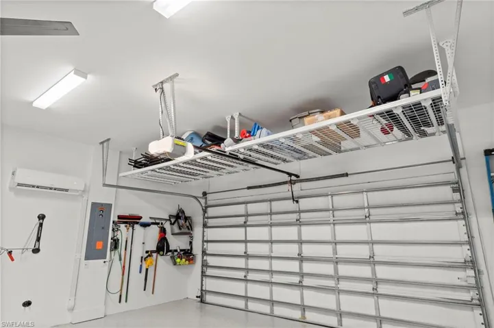 Garage with electric panel, a mini split for heating / cooling, and a garage door opener New CEILING FAN (November 2018, New CEILING STORAGE SYSTEM (January 2019), New HEAVY DUTY EPOXY FLOOR (January 2019), New OVERHEAD DOOR & GARAGE ATTIC INSULATION (January 2019), New CUSTOM CALIFORNIA CLOSET ORGANIZER WALL (February 2020), New MINI-SPLIT AC (May 2020), New electrical panel SURGER PROTECTOR (October 2022), New GARAGE INTERIOR PAINT (July 2023)