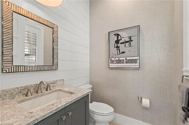 Half bath with vanity and wooden walls New CUSTOM MIRROR (November 2018), New LIGHT FIXTURE (November 2018), New SHIPLAP WALL (May 2020), New WALLPAPER (June 2020)