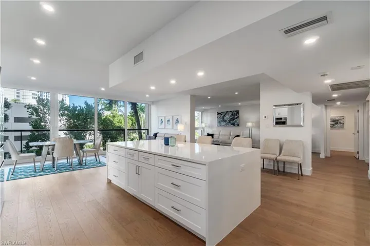 Kitchen featuring white cabinetry, light wood-style floors, recessed lighting, floor to ceiling windows, and a center island
