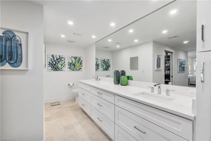 Full bathroom with double vanity, recessed lighting, and a walk in closet
