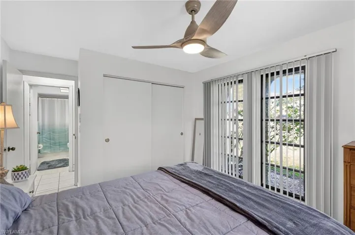 Bedroom with a ceiling fan featuring an integrated light fixture, twin sliding closet doors, and vertically slatted window treatments