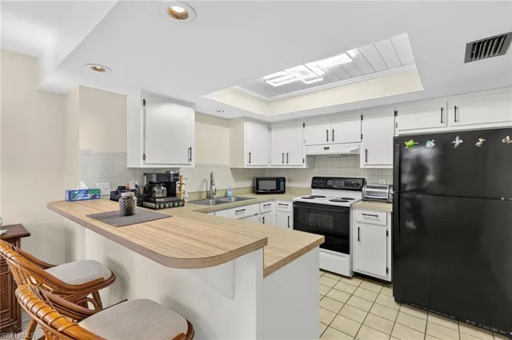 Kitchen featuring white cabinetry, a built-in breakfast bar, recessed lighting, and a skylight