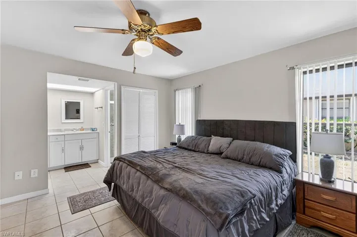 Spacious room featuring tile flooring, a ceiling fan, and large windows with vertical blinds