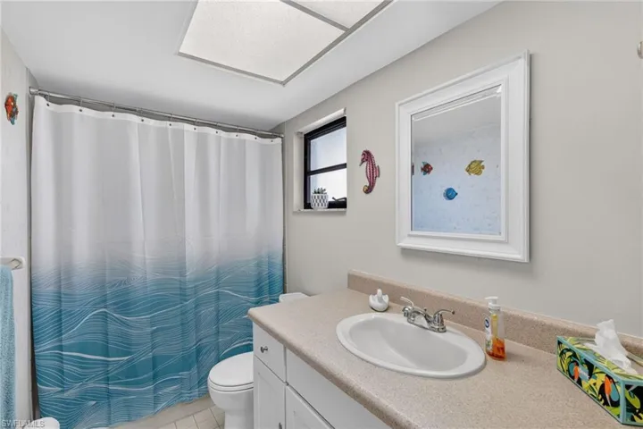 Bathroom featuring a single vanity with an integrated sink, framed mirror, and a window
