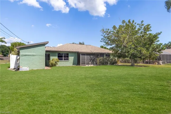 Expansive rear yard featuring a large green lawn, mature trees, and privacy fencing