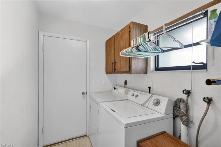 Dedicated utility area featuring overhead wood-finish cabinetry, a frosted window, and a wall-mounted drying rod