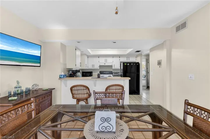 Open-concept kitchen and dining area featuring a breakfast bar with seating, white cabinetry, and a black refrigerator