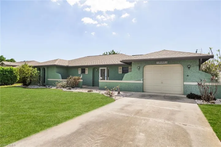 Single-story stucco exterior featuring a two-car garage, concrete driveway, and front lawn