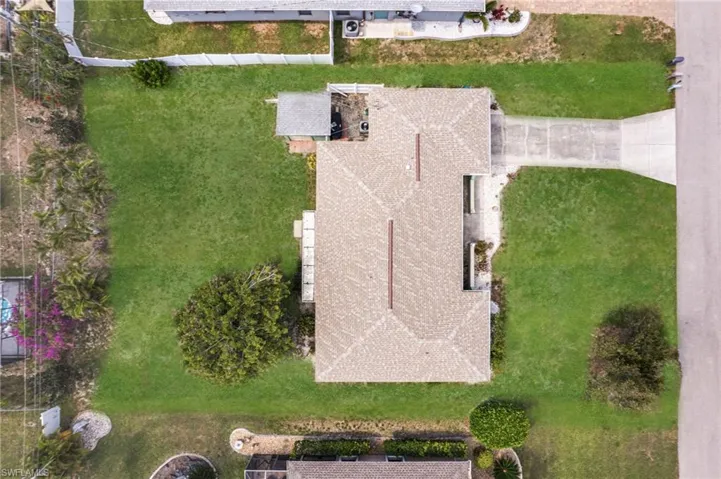 Property featuring a hip roof, extensive lawn, mature trees, and a concrete driveway