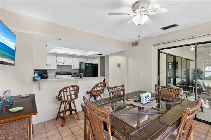 Open-concept living space with tile flooring throughout, a kitchen pass-through bar, white cabinetry, and sliding glass doors