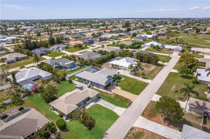 Aerial perspective showcasing a residential area with single-family homes, green lawns, and paved roads