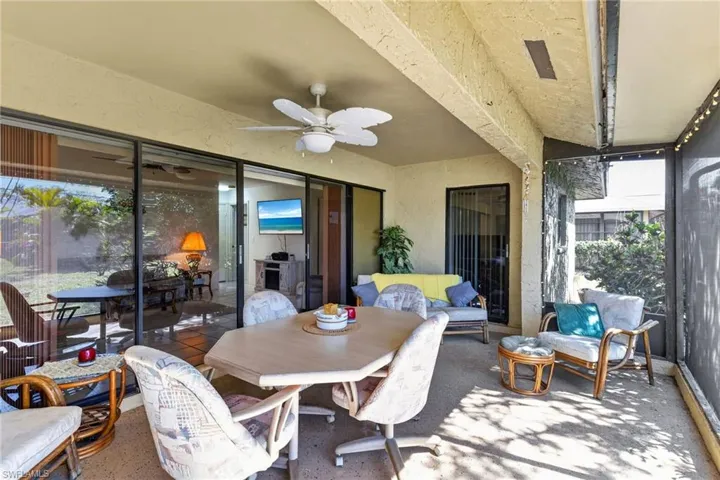 Covered patio featuring a ceiling fan, concrete flooring, screened enclosure, and large sliding glass doors